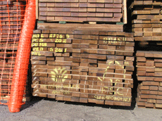 Pallet of reddish-brown wood, seen from the side, with yellow paint showing it is cumaru, imported by Timber Holdings Limited from Precious Woods and is FSC certified