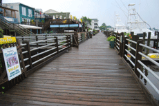 Wooden walkway with buildings on one side and boats on the other