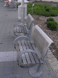 Two outdoor benches with metal backs and seats made of wooden slates