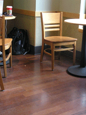 Reddish-colored wood flooring with chair and table