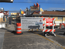 Boardwalk ending behind signs, with buidlings on either side